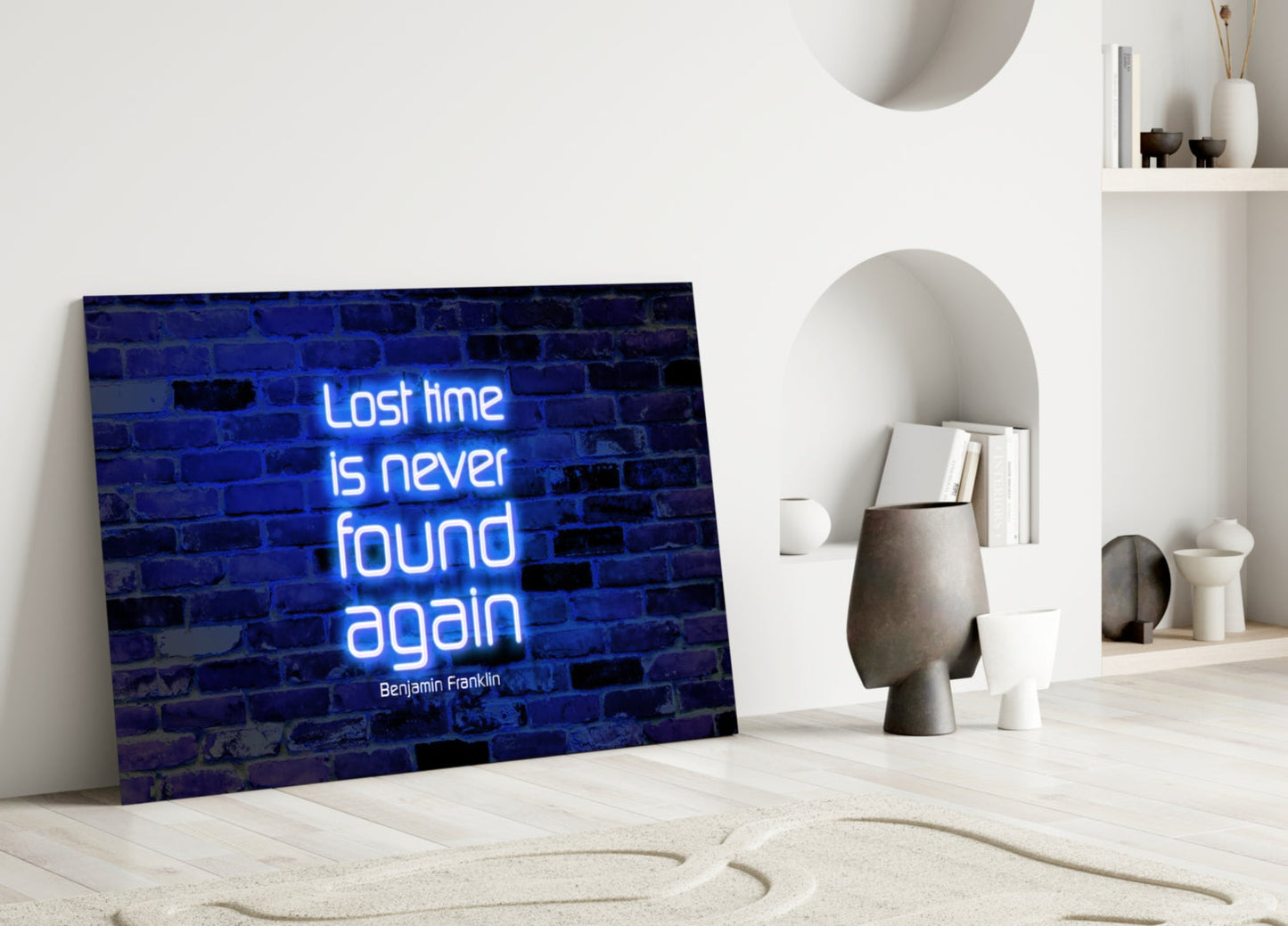 Blue neon glass art displaying "Lost time is never found again" quote leaning against white wall with decorative objects.
