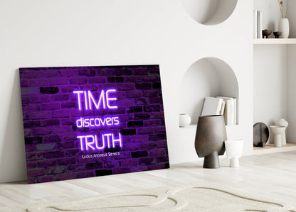 Purple neon glass wall art displaying "TIME discovers TRUTH" quote leaning against white interior wall with decorative objects.