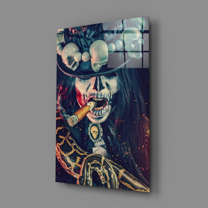 Angled view of glass wall art depicting a skull with cigar, ornate chains, and feathered details in dark tones with red and gold accents.