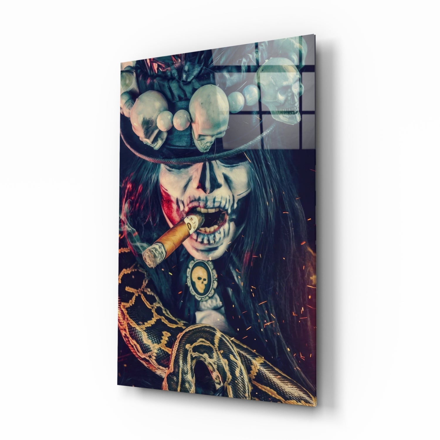 Angled view of glass wall art depicting skull with cigar, ornate chains, and feathered wing detail in warm orange and cool teal tones.