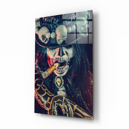 Angled view of glass wall art depicting skull with cigar, ornate chains, and feathered wing detail in warm orange and cool teal tones.