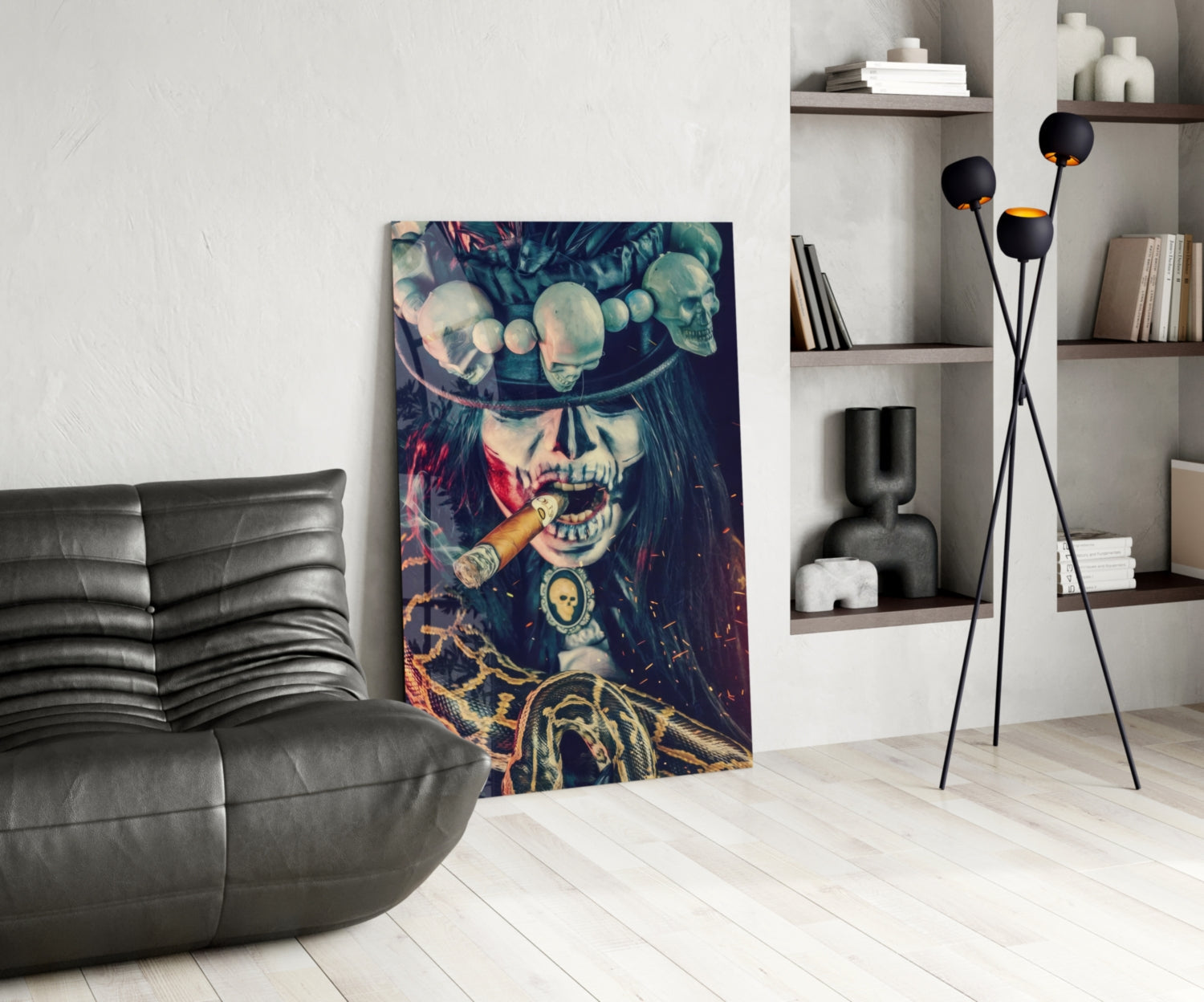 Colorful glass wall art depicting skull-faced figure wearing hat and smoking cigar, displayed in modern living room with black leather sofa and shelving.