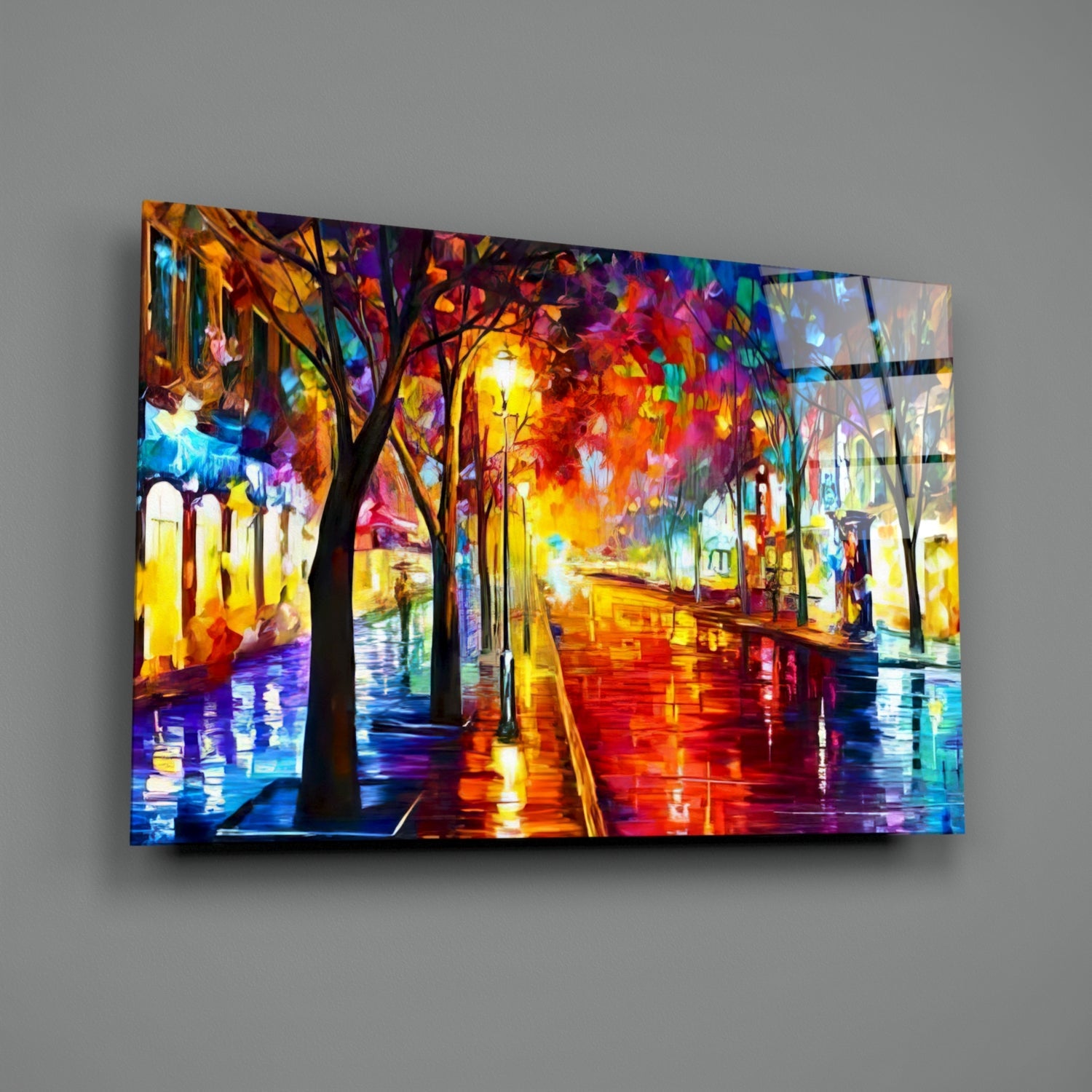 Illuminated glass wall art displaying a colorful nighttime street scene with glowing trees, wet pavement, and vibrant yellow, orange, and blue light reflections mounted on gray wall.