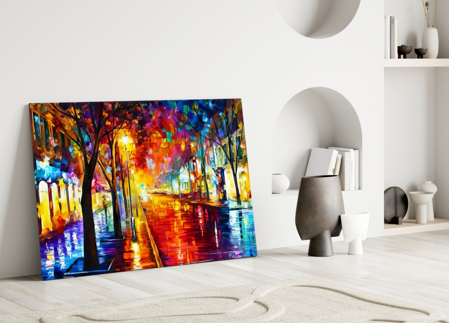 Colorful glass wall art leaning against white wall shows vibrant street scene with illuminated trees, buildings, and wet pavement in blues, reds, yellows, and purples.