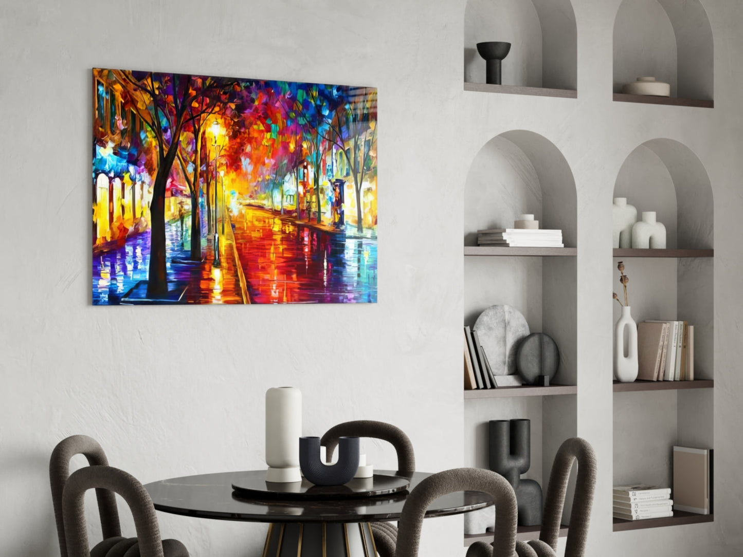 Vibrant colorful street scene glass art hanging above black dining table in modern white interior with built-in shelving.