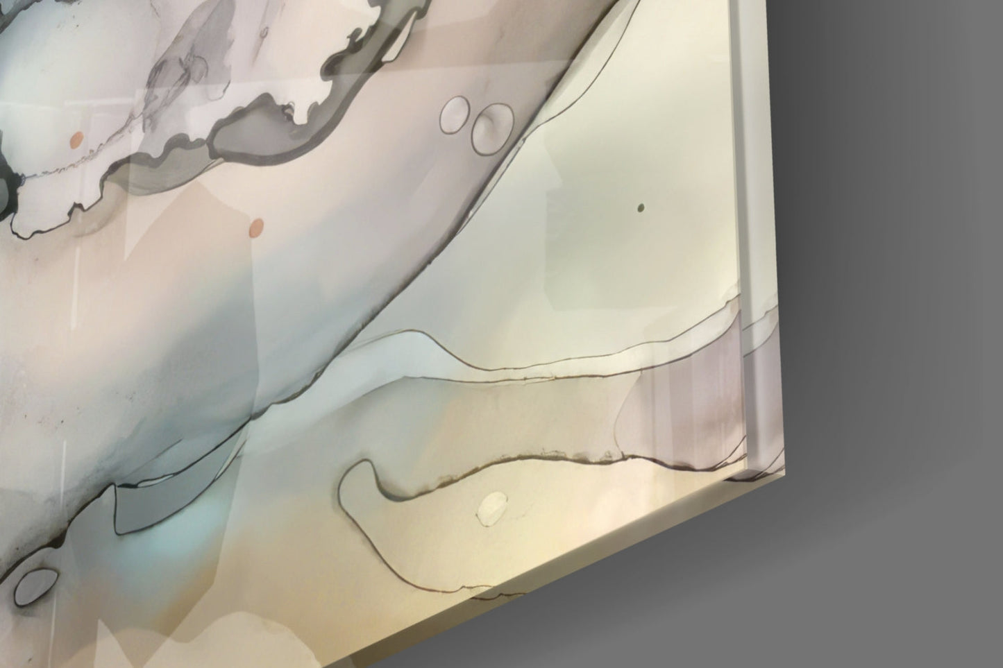 Close-up overhead view of layered glass wall art with organic curved lines in gray and beige tones on cream background.