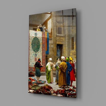 Glass wall art depicting a Middle Eastern carpet bazaar scene with figures in colorful robes examining ornate textiles displayed indoors.