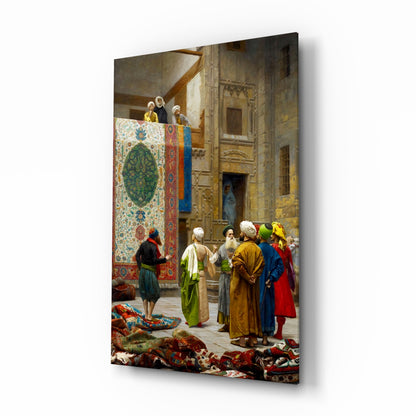 Glass wall art displaying an Orientalist painting of merchants and customers examining colorful carpets in an ornate Middle Eastern interior courtyard.
