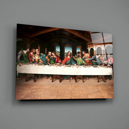 Glass wall art depicting the Last Supper scene with thirteen figures seated at a table, mounted on a gray wall.