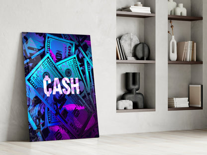 Neon blue and magenta glass wall art with "CASH" text and dollar bill imagery, leaning against white wall beside shelving unit.