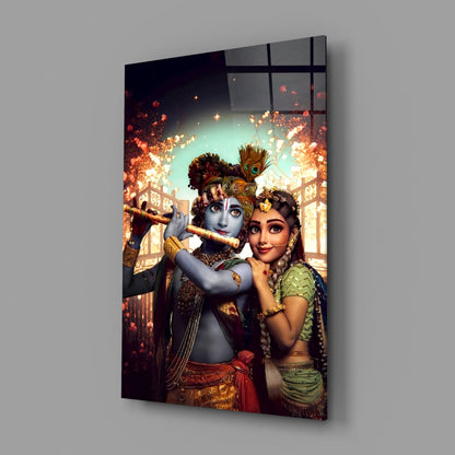 Angled view of Krishna and Radha glass wall art displaying ornate figures with golden jewelry against glowing turquoise and orange architectural background.