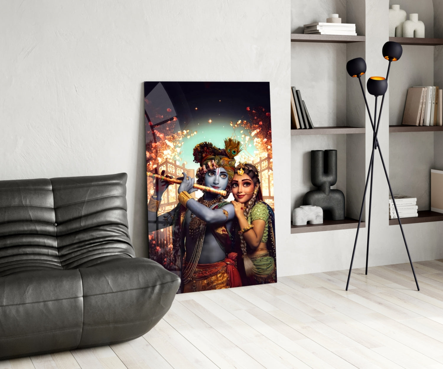 Krishna and Radha glass wall art displayed in modern living room with gray sofa, white shelving, and black floor lamp.