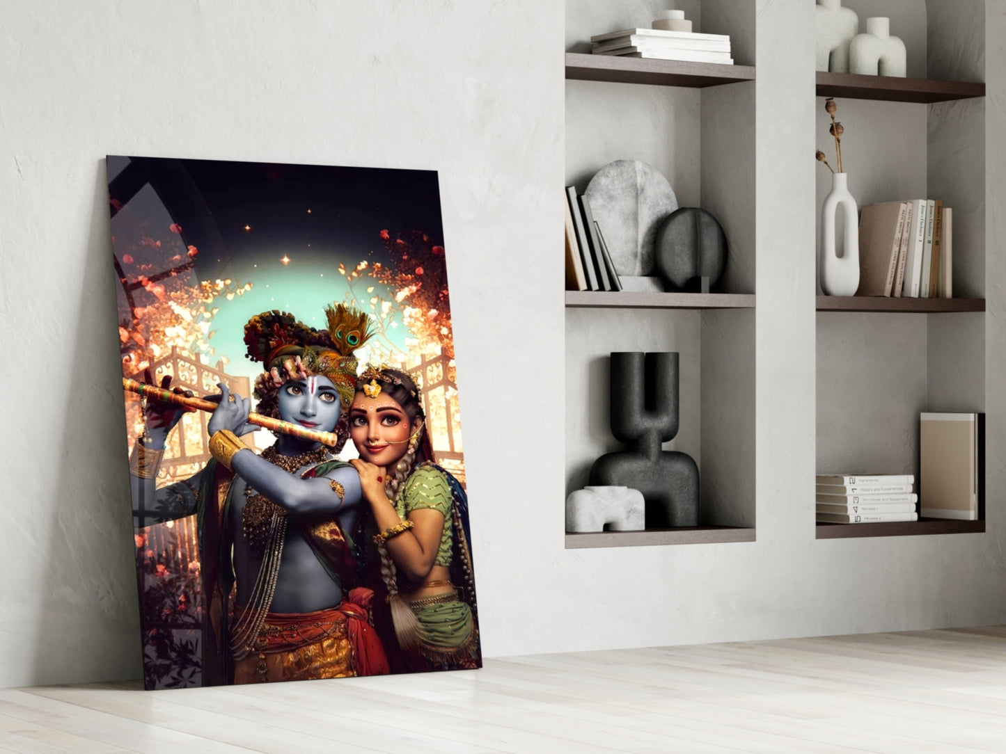 Krishna and Radha glass wall art leaning against white wall beside shelving unit displaying decorative objects and books.