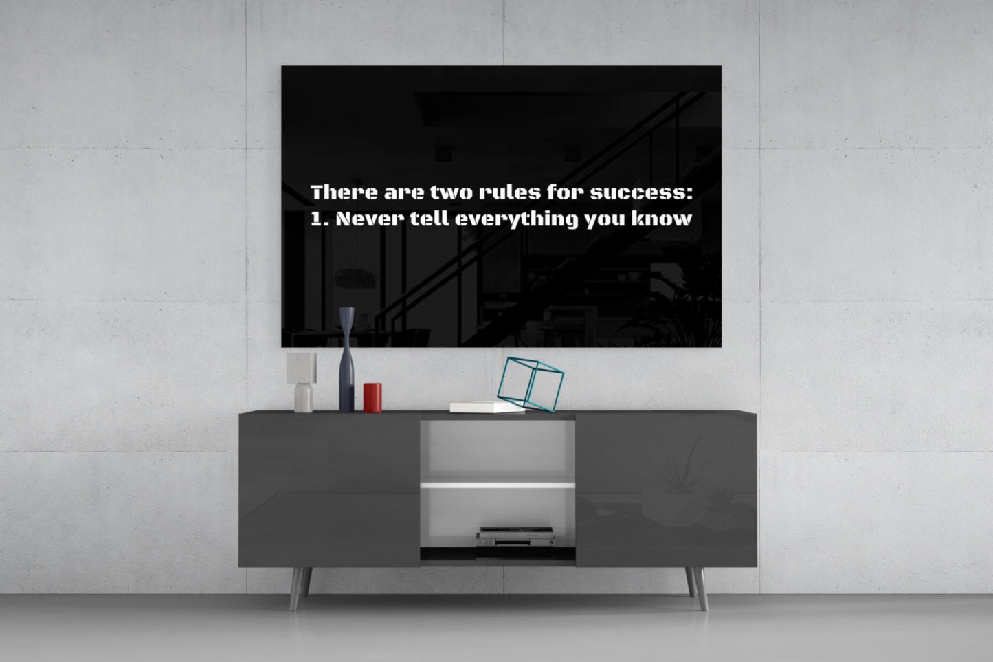 Black glass wall art displaying white text "There are two rules for success: 1. Never tell everything you know" mounted above gray media console.