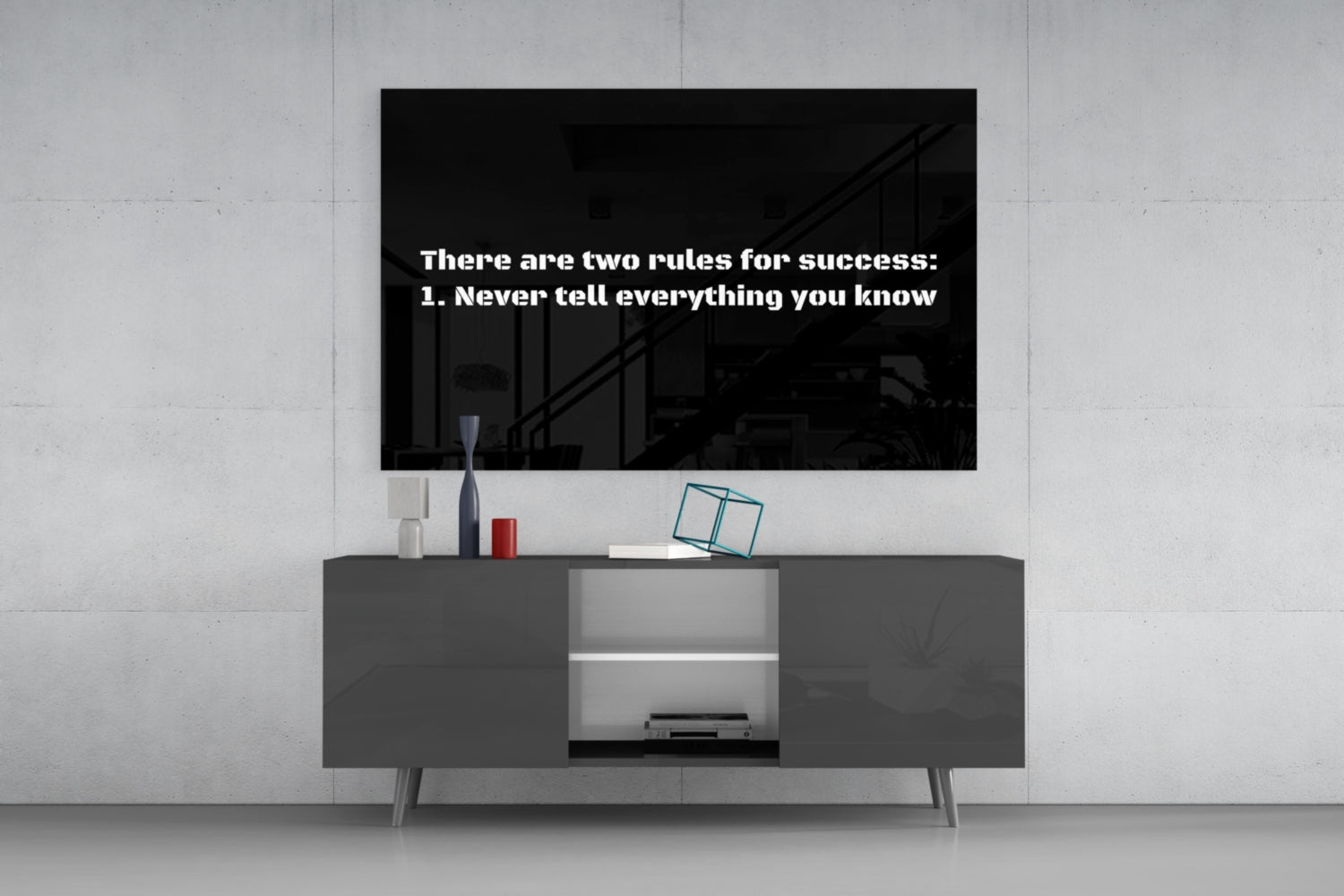 Black glass wall art displaying white text "There are two rules for success: 1. Never tell everything you know" mounted above gray media console.