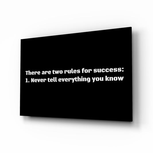 Black glass wall art panel displayed at an angle showing white text about two rules for success.