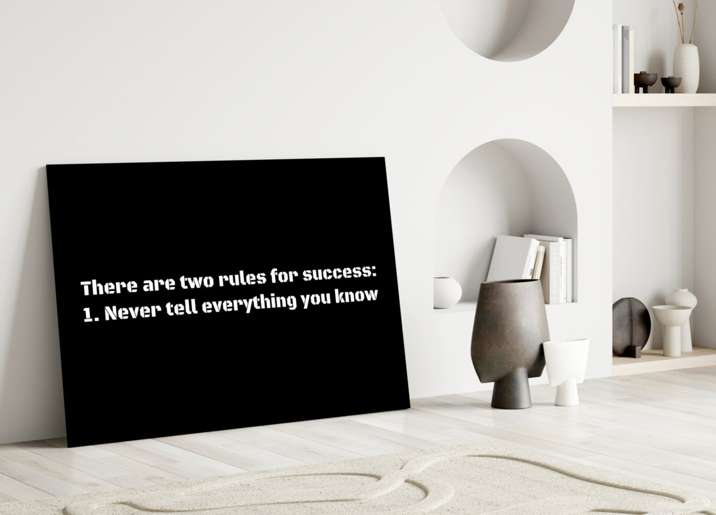 Black glass wall art displaying white text "There are two rules for success: 1. Never tell everything you know" leaning against white interior wall with shelving and decorative objects.