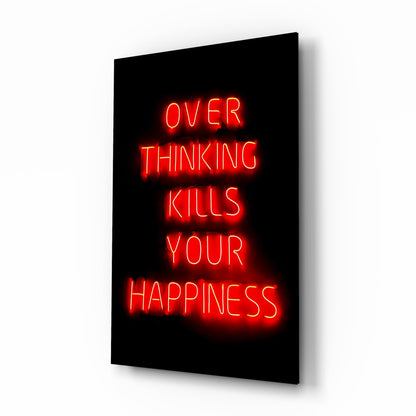 Red neon text reading "OVER THINKING KILLS YOUR HAPPINESS" glowing on black glass panel displayed at an angle.
