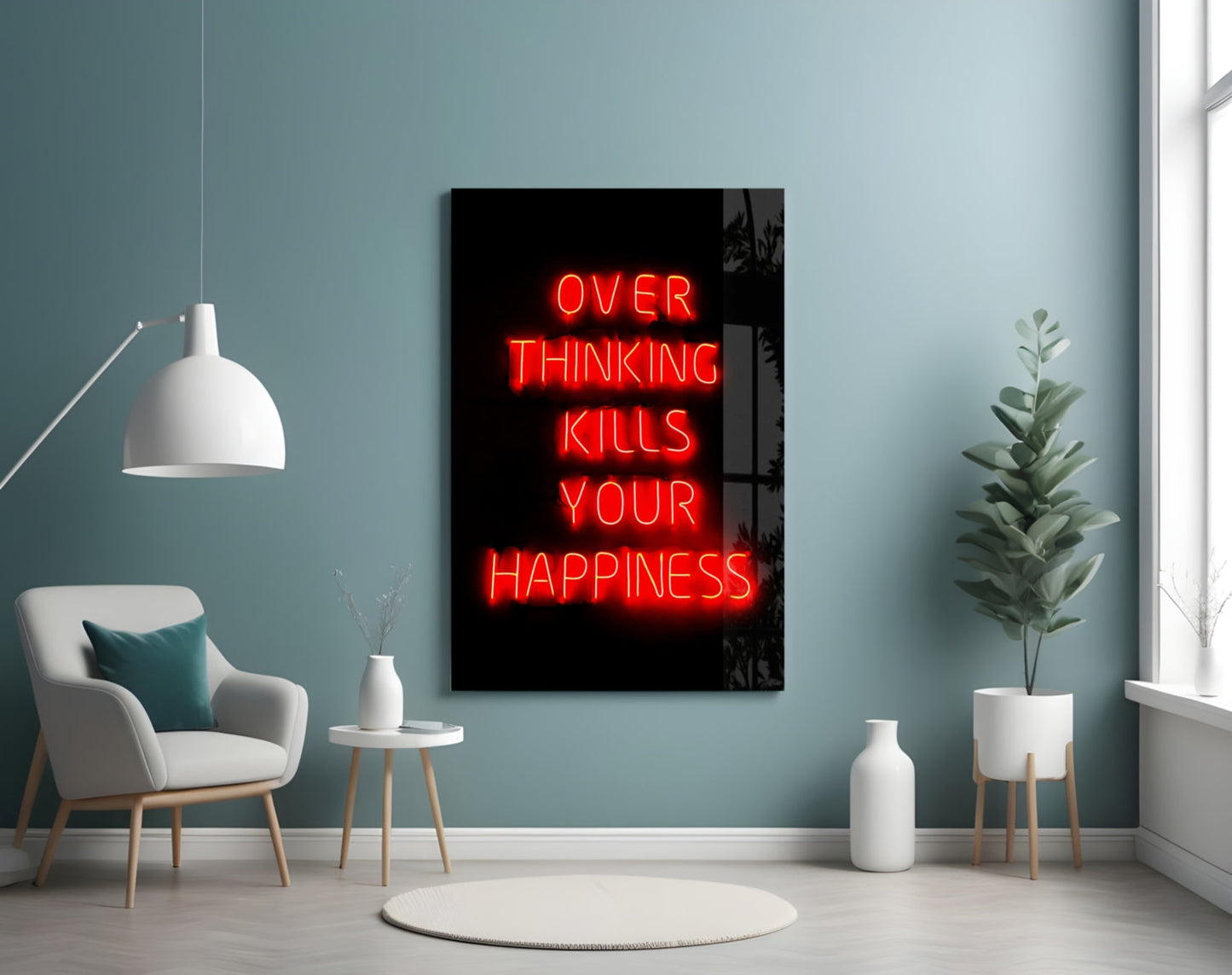 Red neon "OVER THINKING KILLS YOUR HAPPINESS" text on black glass panel displayed on teal wall beside chair and plant.