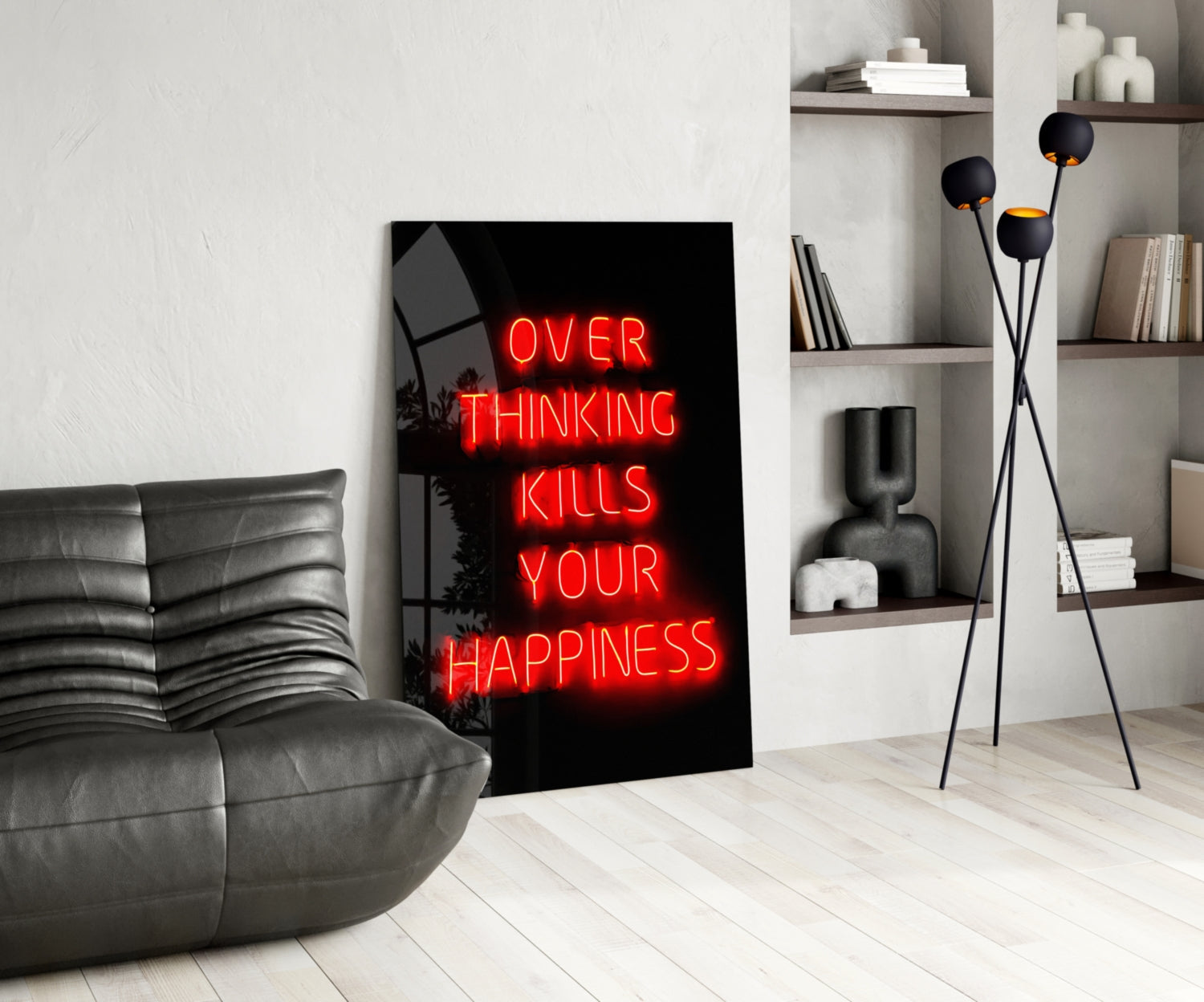 Red neon "OVER THINKING KILLS YOUR HAPPINESS" text on black glass leaning against white wall in modern living room setting.