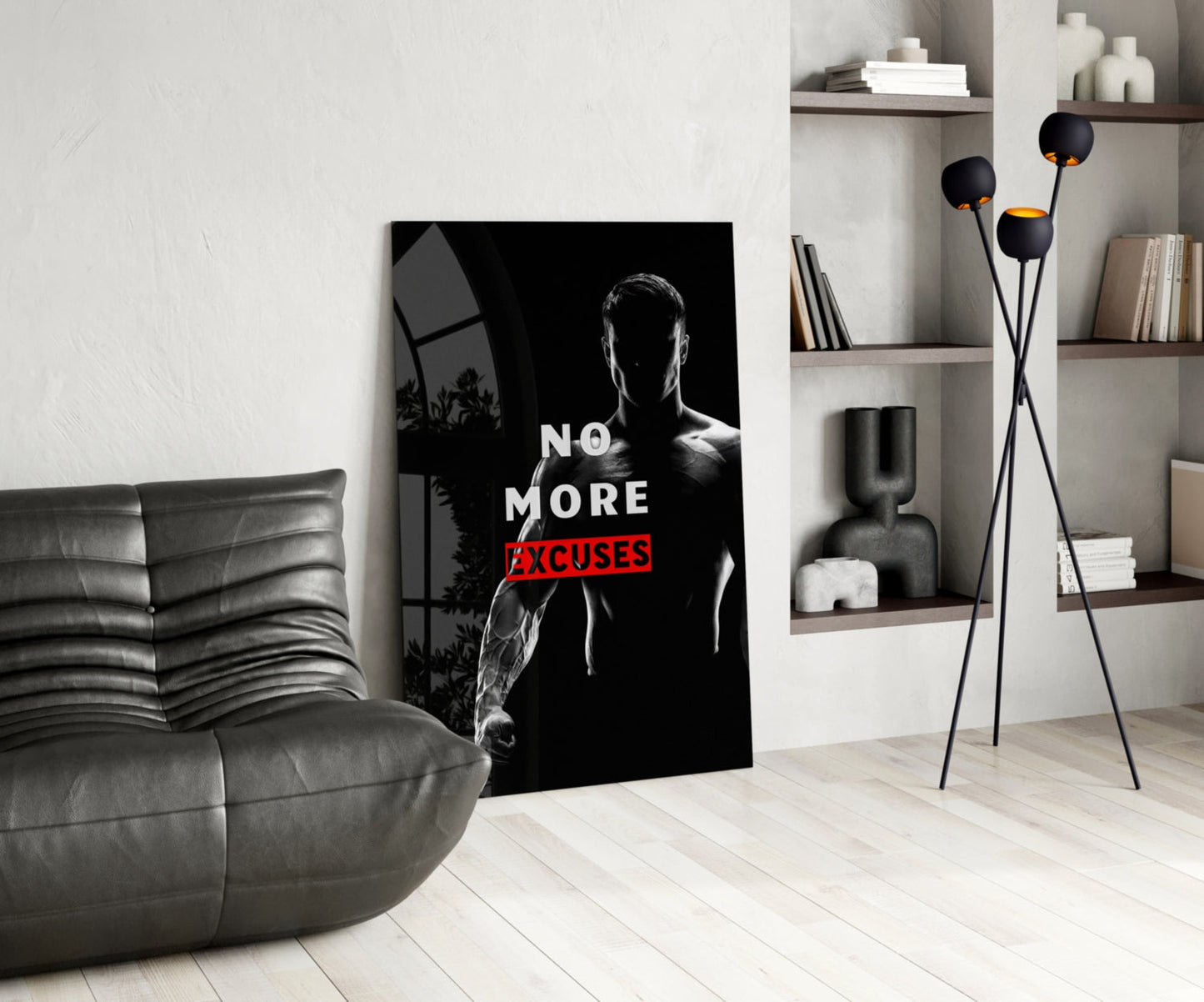 Black and white glass wall art featuring a muscular man with "NO MORE EXCUSES" text in red, displayed in modern living room with gray sofa and shelving.