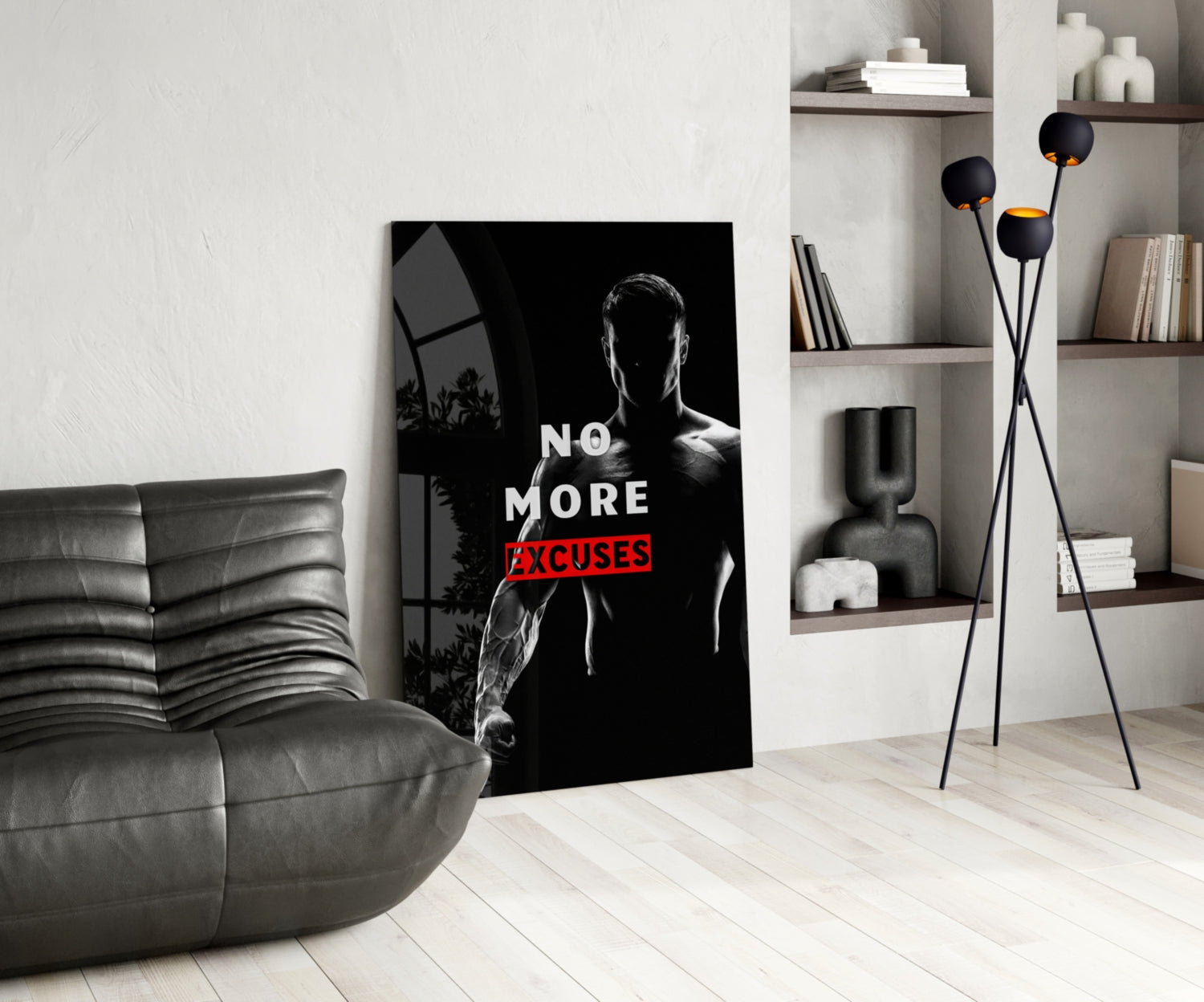 Black and white glass wall art featuring a muscular man with "NO MORE EXCUSES" text in red, displayed in modern living room with gray sofa and shelving.