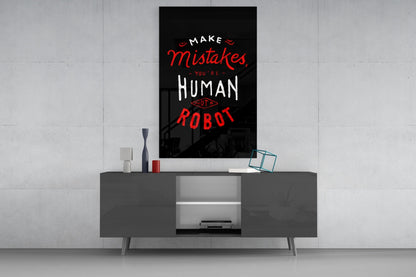 Black glass wall art with red and white text reading "Make Mistakes You're Human Not A Robot" displayed above a dark gray media console.