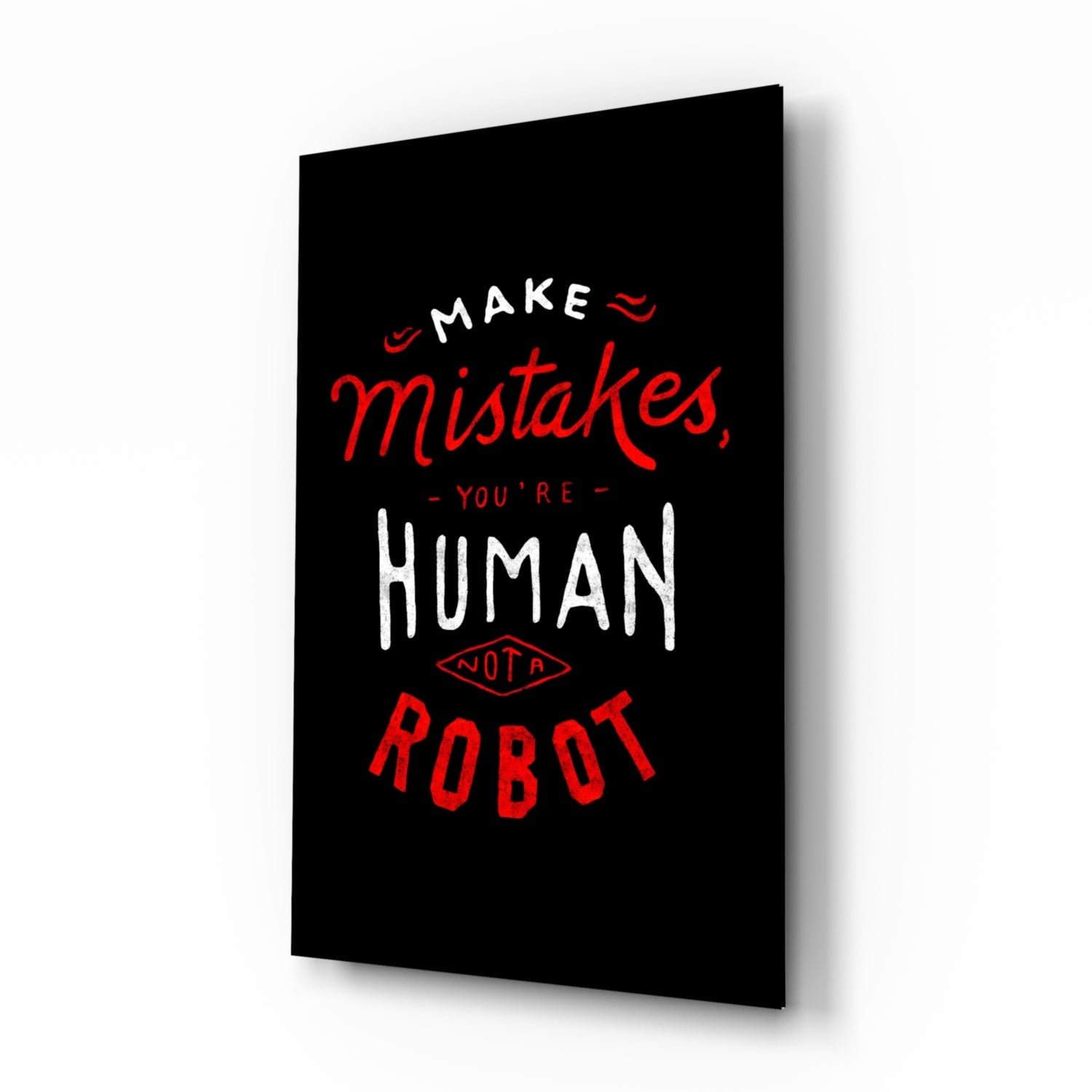 Black glass wall art panel angled right, displaying red and white text reading "Make mistakes, you're human not a robot" with decorative elements.