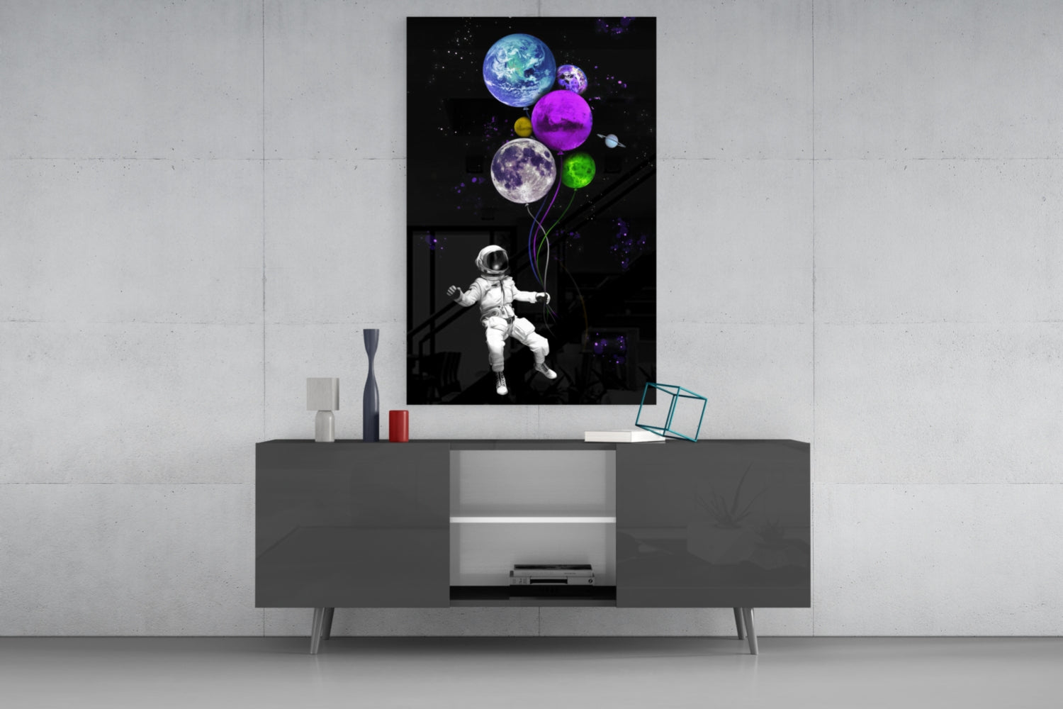Astronaut holding colorful planet balloons displayed as glass wall art above modern gray media console.