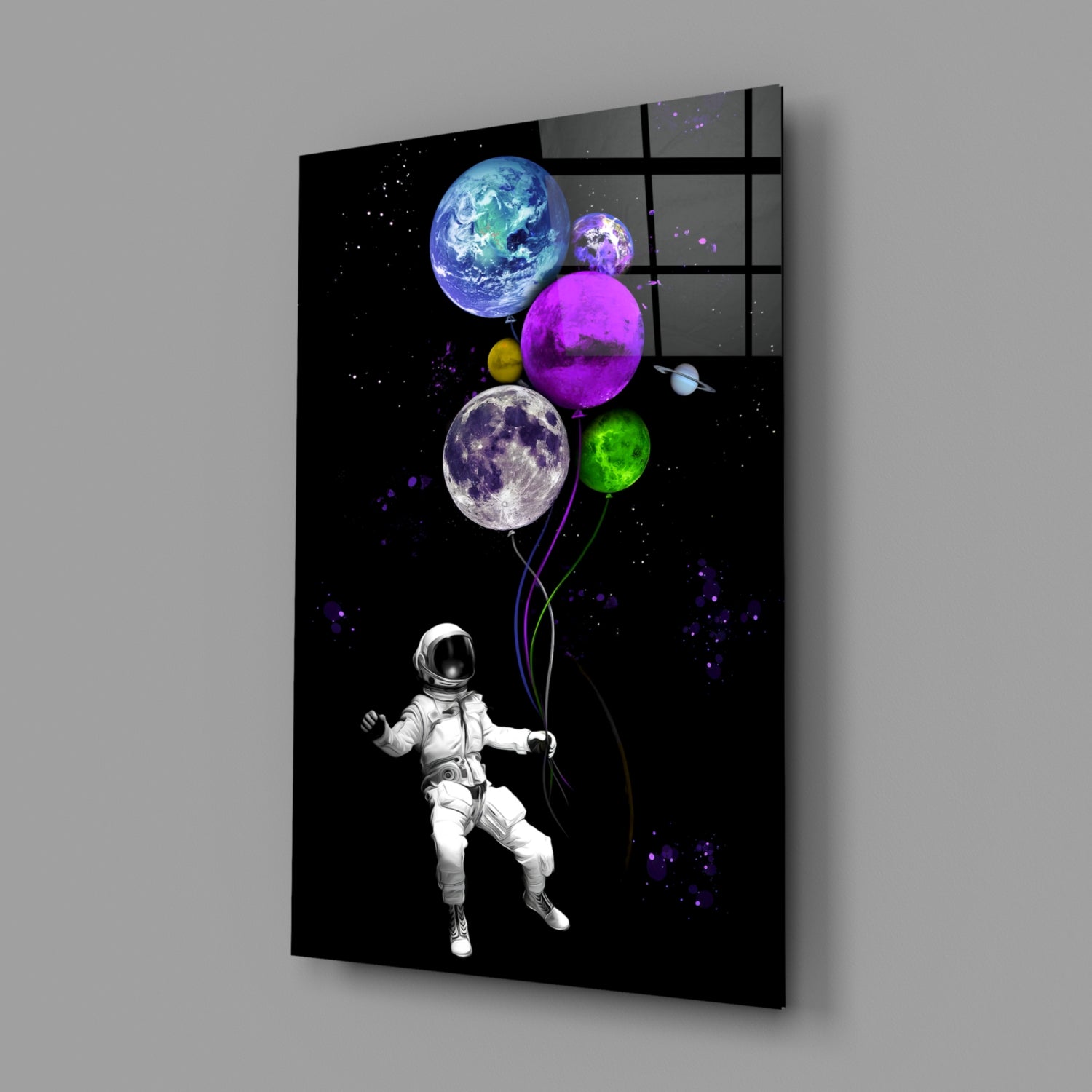 Angled product view of black glass wall art featuring a white astronaut holding colorful planet balloons against a starry space background.