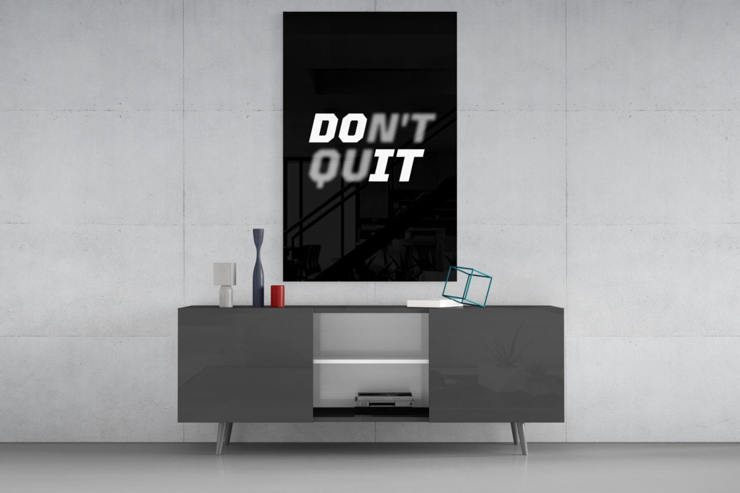 Modern minimalist living room with "Don't Quit" motivational text displayed on black glass wall art above dark grey media console.