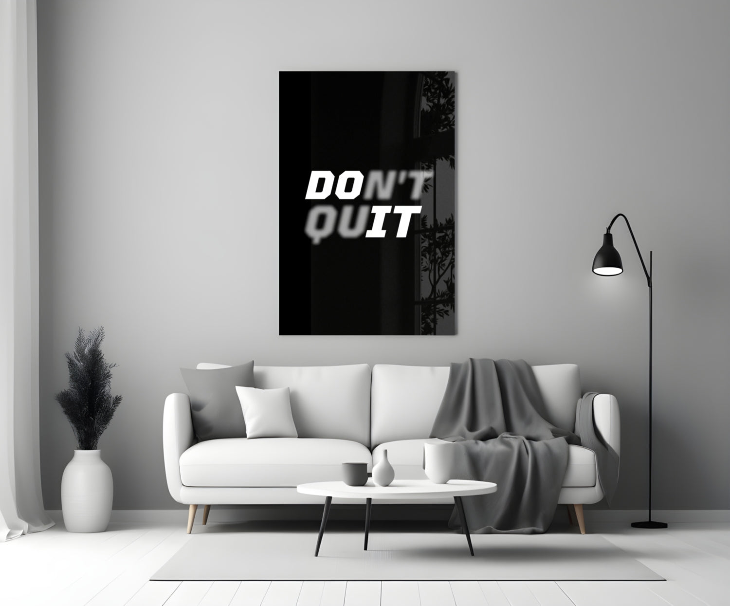Don't Quit" black glass wall art displayed above white sofa in minimalist living room with gray accents.