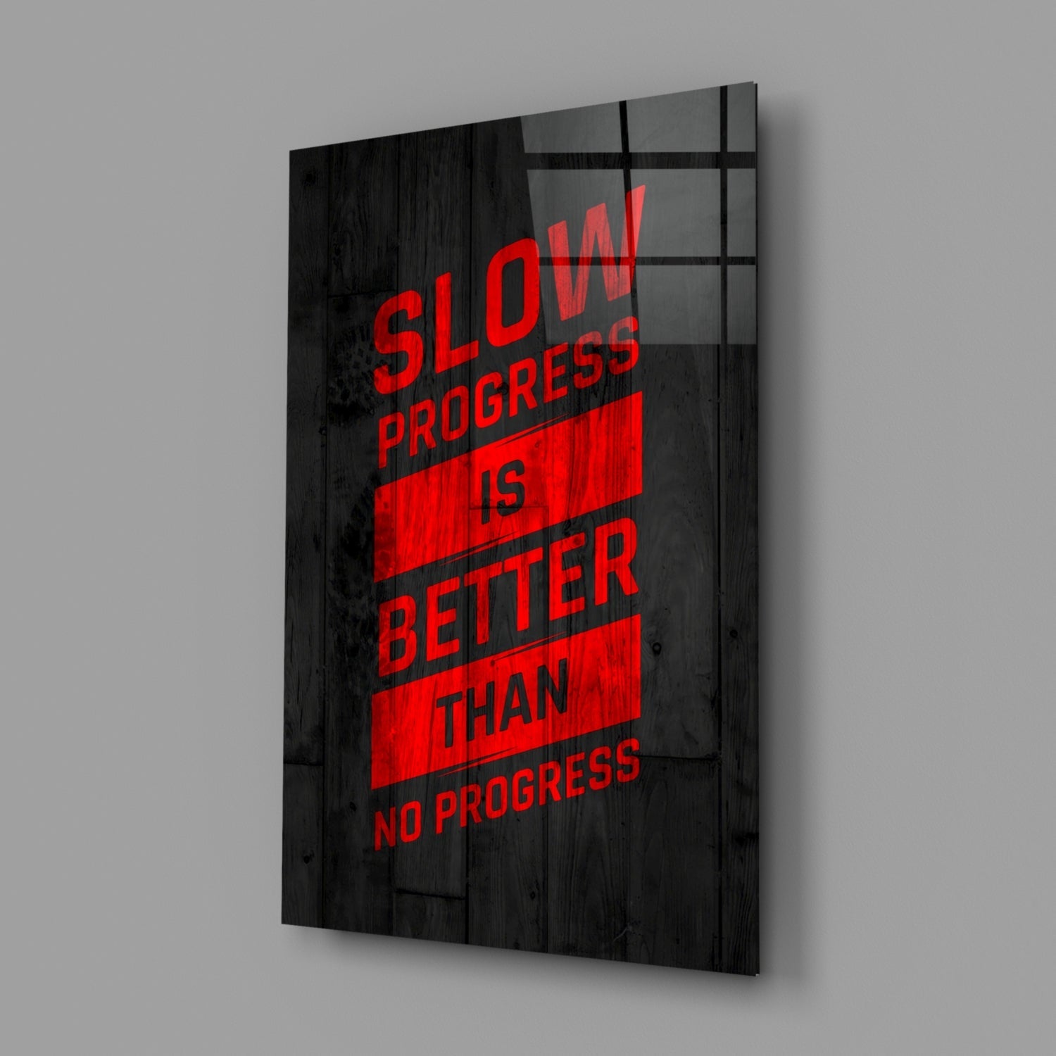 Angled view of black wooden wall art with red text reading "Slow Progress is Better Than No Progress" behind glass panel.