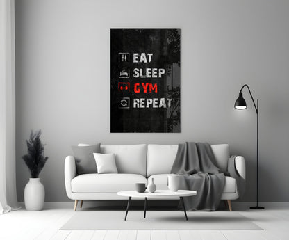 Black glass wall art with white and red neon-style text reading "Eat Sleep Gym Repeat" displayed above a white sofa in a modern living room.
