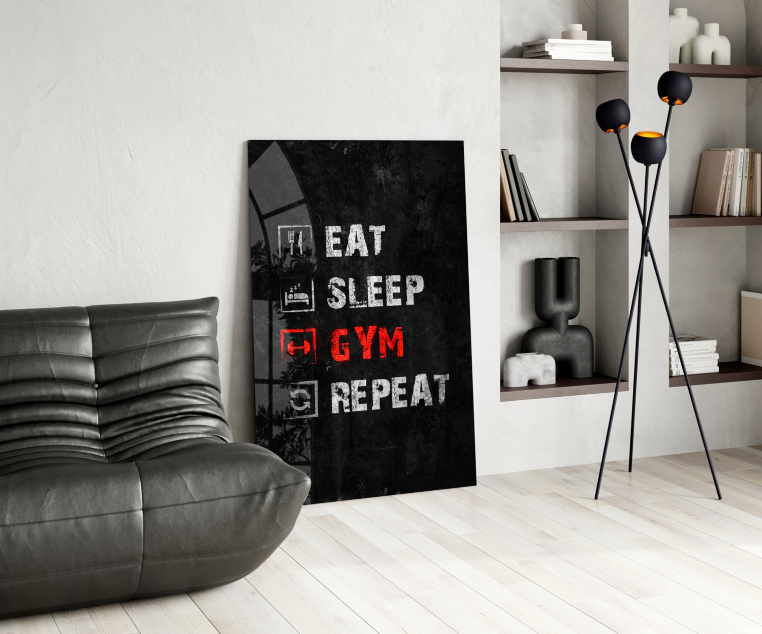 Black glass wall art with white and red text reading "Eat Sleep Gym Repeat" displayed in modern living room with gray sofa and shelving.