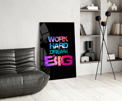 Black glass wall art displaying "WORK HARD DREAM BIG" in blue and pink neon-style text, displayed in a modern living room interior.
