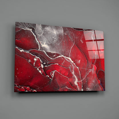 Red Marbellous Glass Wall Art displayed at an angle against a gray wall, showing swirled red and white marble patterns with metallic accents.
