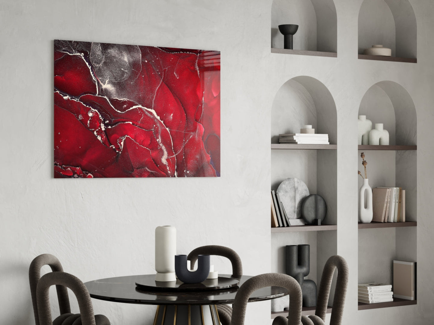 Red Marbellous glass wall art displaying abstract white veining on deep red background, hung above round black dining table with gray chairs.