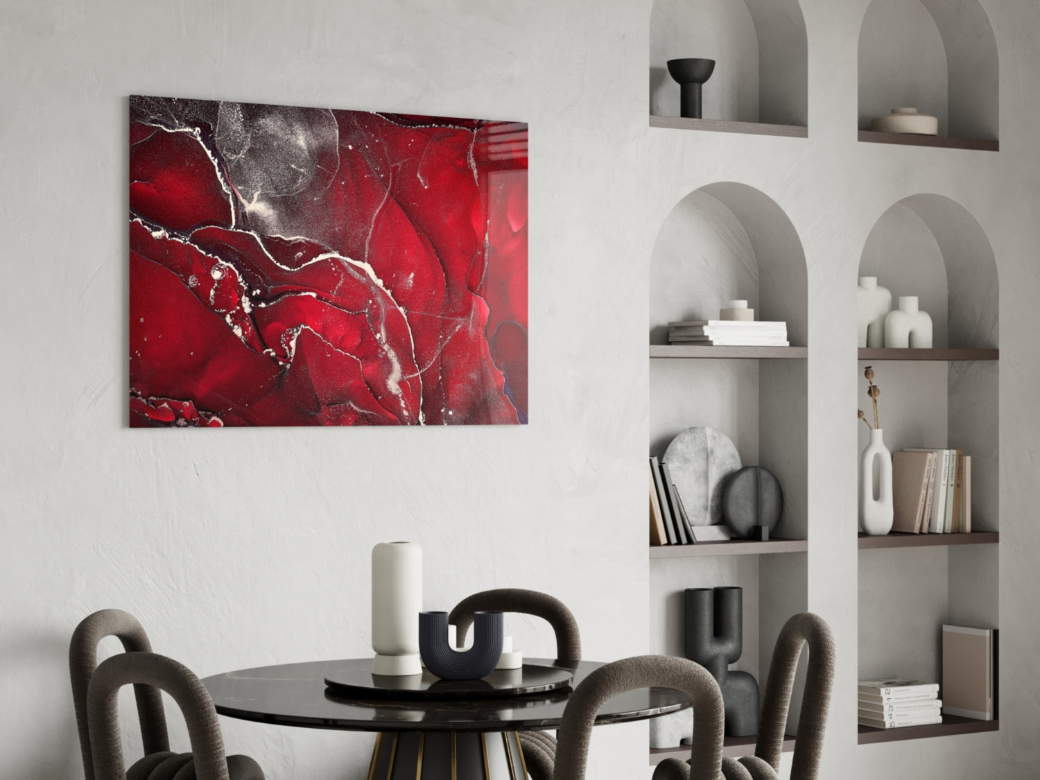 Red Marbellous glass wall art displaying abstract white veining on deep red background, hung above round black dining table with gray chairs.