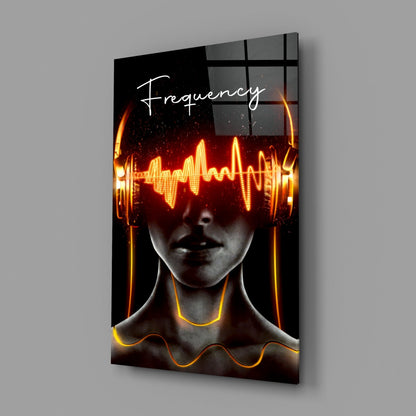Angled view of glass wall art featuring a figure with neon orange sound wave graphics across eyes and neck, "Frequency" text, mounted on gray wall.