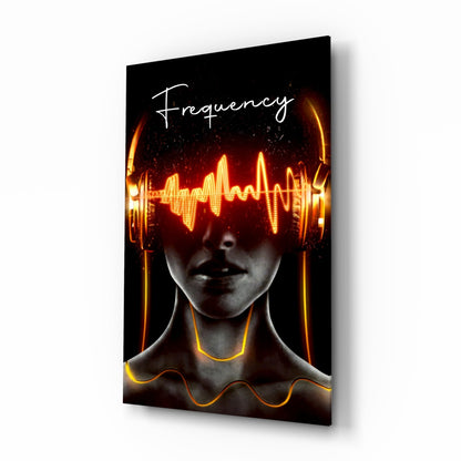 Angled view of glass wall art featuring a face with glowing neon yellow and orange soundwave graphics across the eyes and neon tubing around the neck against black background, with "Frequency" text at top.