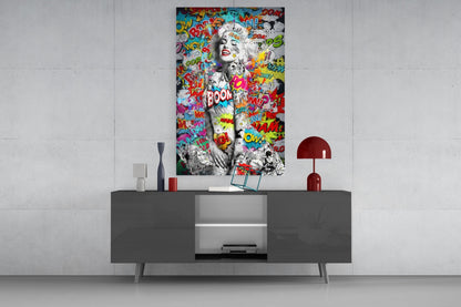Colorful pop art graffiti glass wall art featuring black and white portrait with comic book text displayed above gray modern console table.