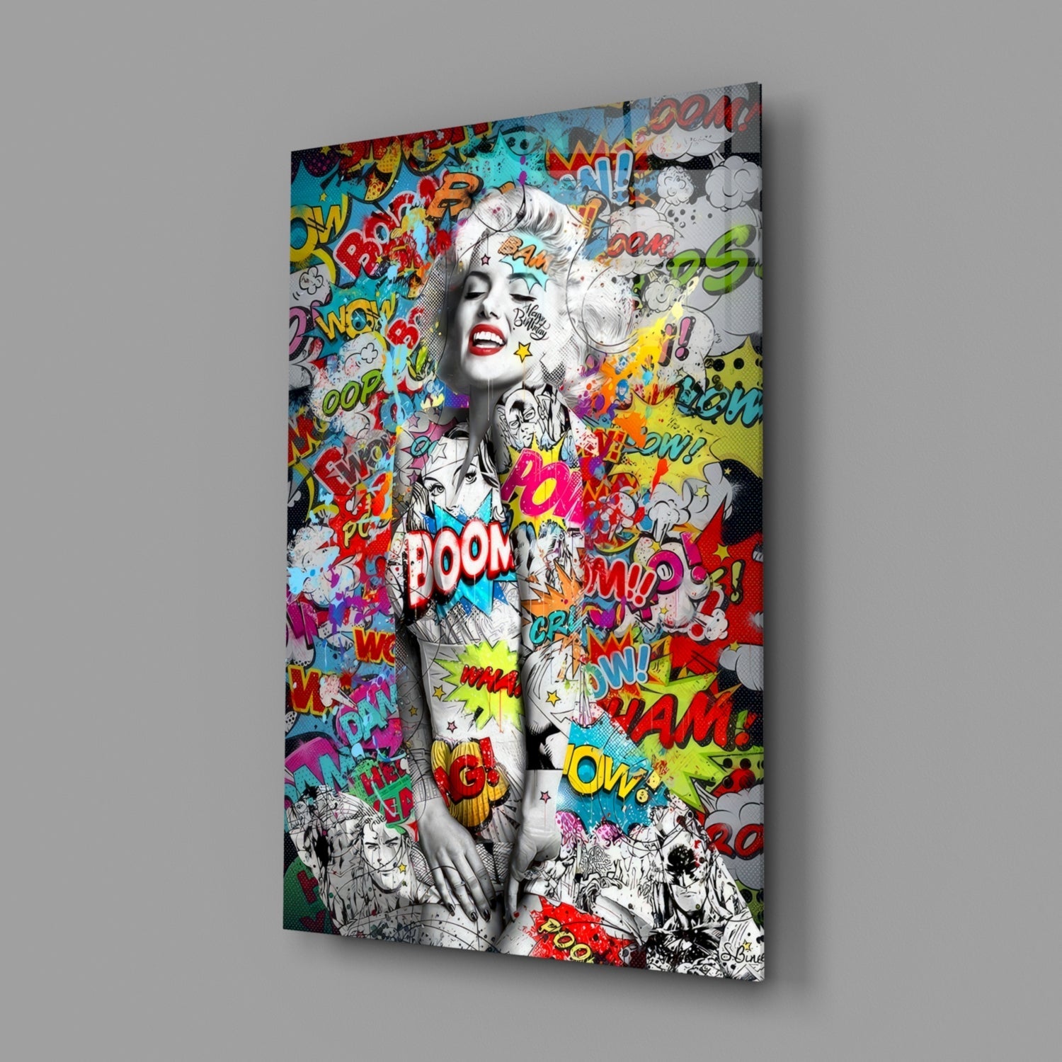 Angled view of glass wall art featuring black and white portrait with colorful comic book graffiti text and speech bubbles overlay.