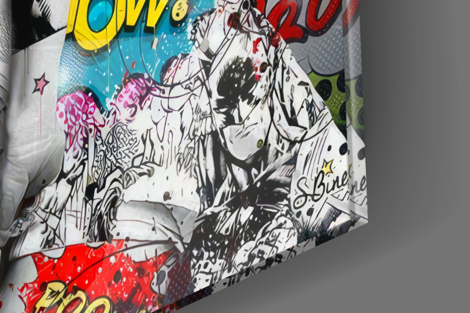 Close-up angled view of graffiti glass wall art featuring black ink line drawings with colorful accents in yellow, pink, red, and blue on white glass surface.