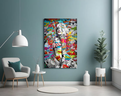 Pop art style glass wall art featuring a black and white portrait with colorful comic book words and red lips displayed in a modern living room interior.