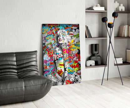 Colorful pop art graffiti glass wall art depicting a woman's face with comic book text and speech bubbles displayed in modern living room setting.