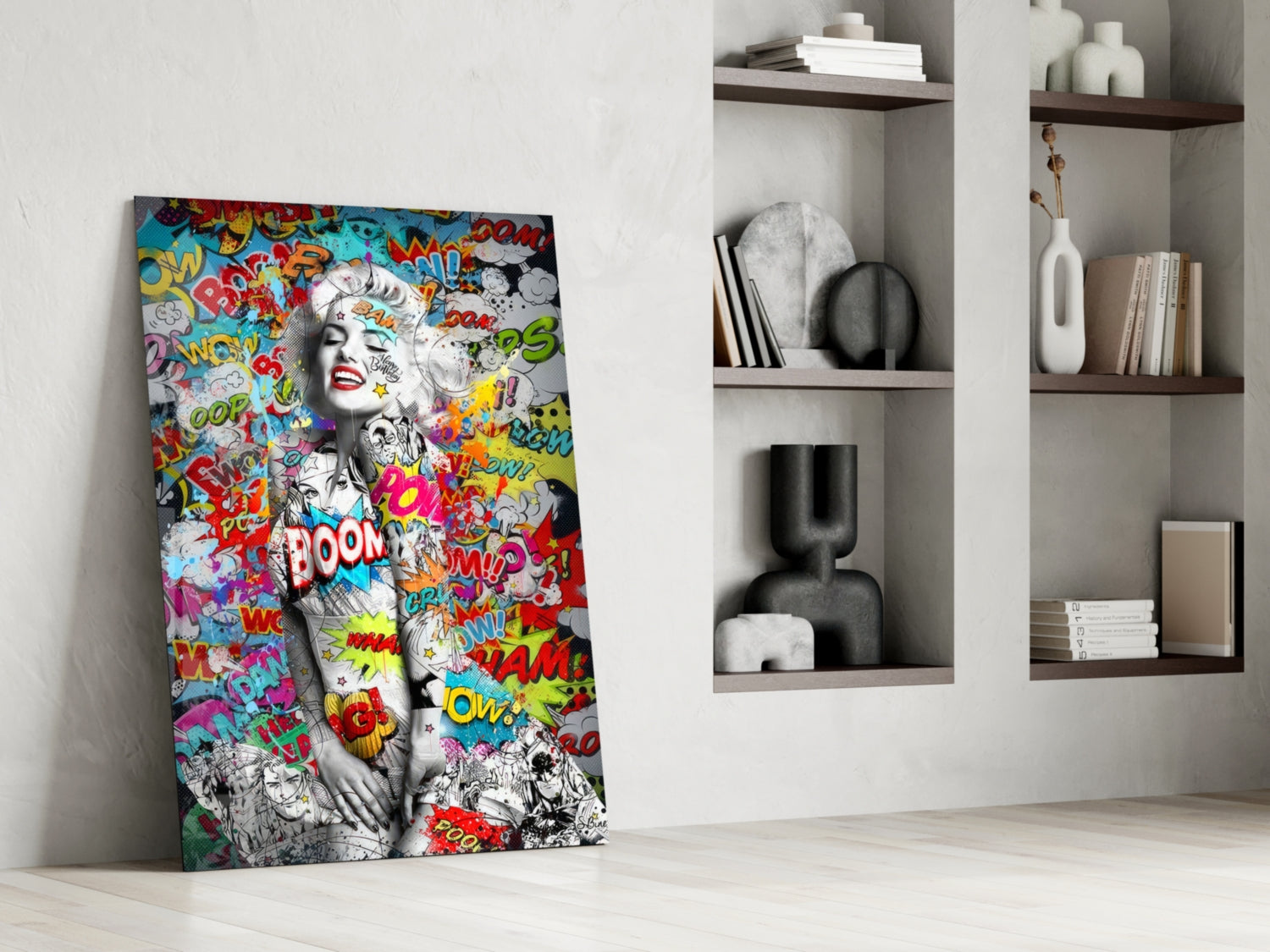 Colorful pop art graffiti glass wall art leaning against white wall beside shelving unit, featuring monochrome portrait with comic book text overlays in red, yellow, and blue.