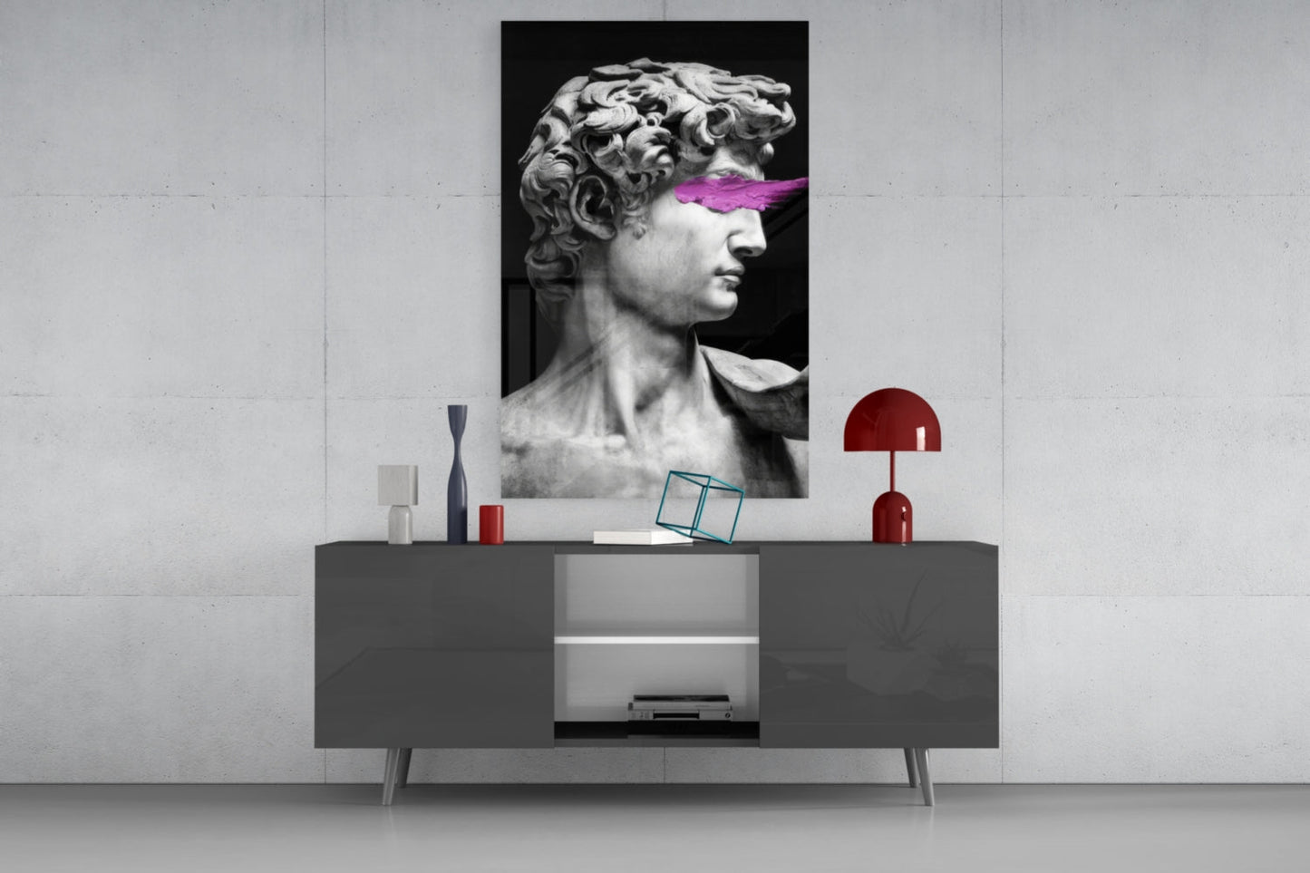 Modern interior display featuring black glass wall art of classical bust with magenta stripe above gray sideboard with red accents.