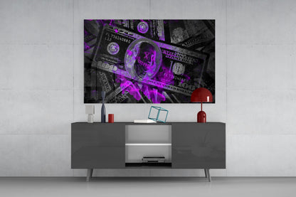 Purple and magenta neon-lit US dollar bills glass wall art displayed above gray media console in modern living room setting.