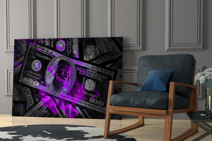 Purple and black neon dollar bill glass wall art displayed in modern living room beside wooden chair with dark cushions.